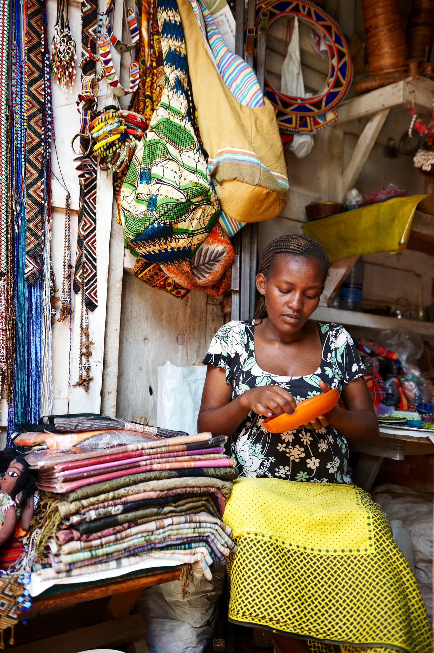 Kenyan woman crafting with colorful textiles